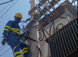 A photo of a Kenya Power staff member atop an electricity pole.